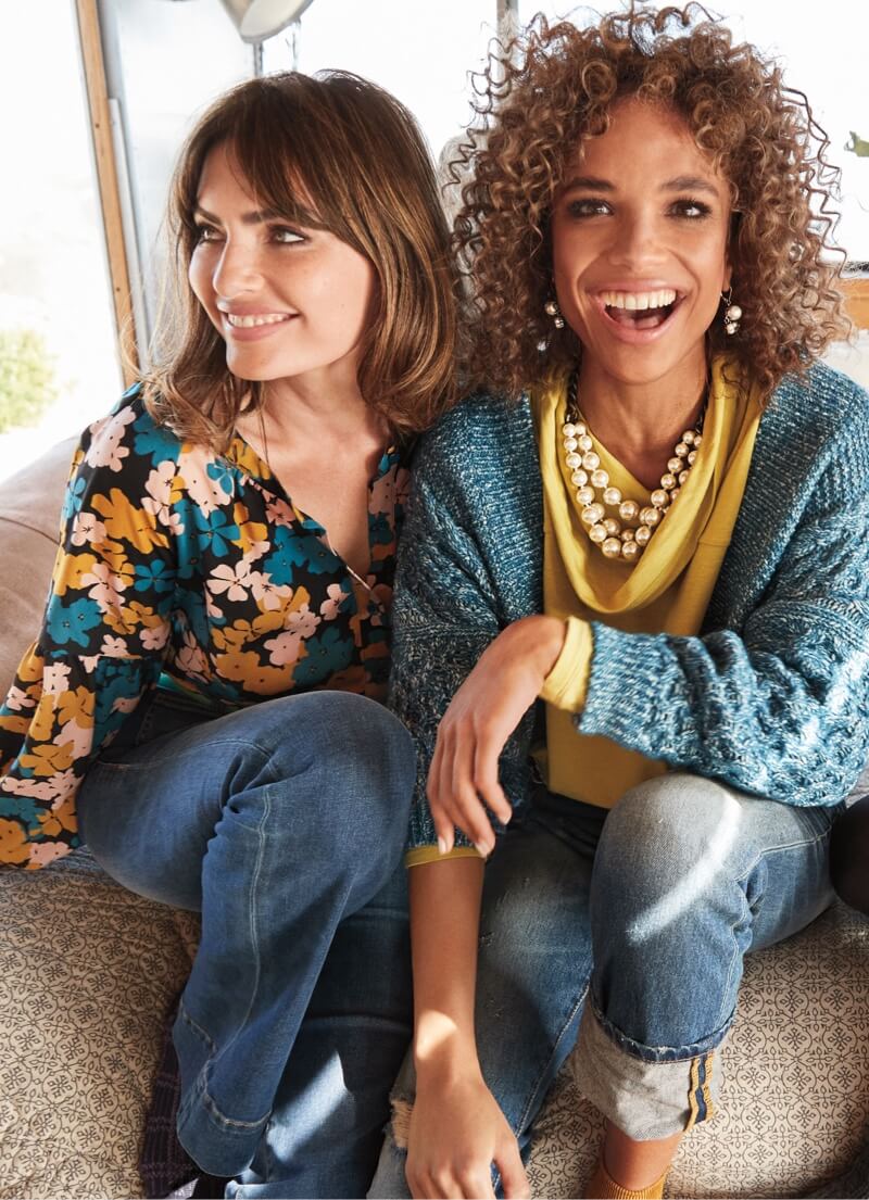 Two models wearing Fall 2021 products fron the new collection. First model wearing Favorite Blouse in Flower Drop, Patch Pocket in Trader Wash. Second model wearing Astral Cardigan in Celestial Blue, Ease Turtleneck in Bright Moss, 100% Boyfriend in Craftsman Wash, Clutch Earrings in Antique Silver.
