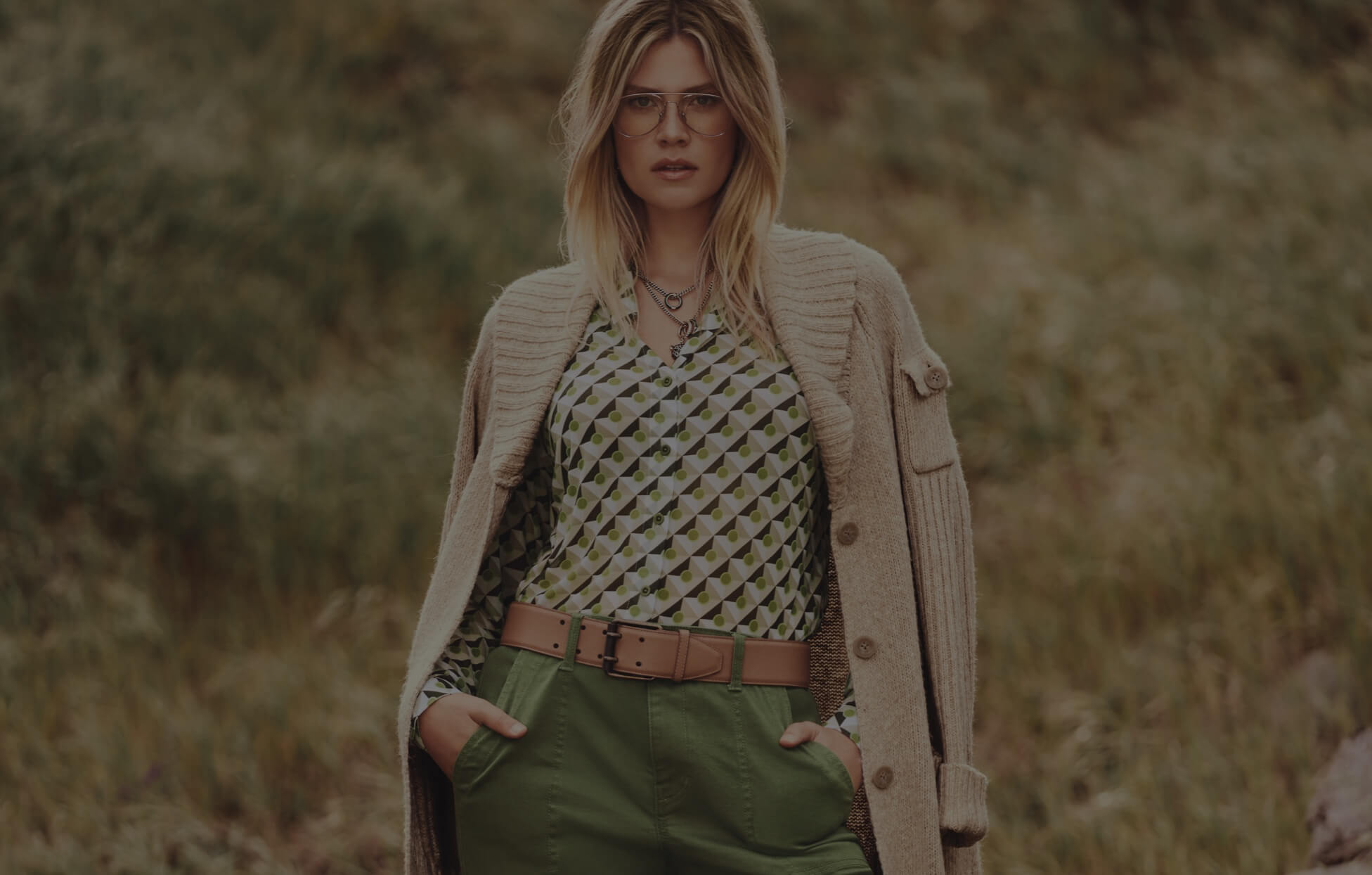 Model in background wearing Steady Cardigan in Wheat, Mosaic Mesh Top in Tile Print, Compass Pant in Army Green, and Jaguar Necklace in Gold. 