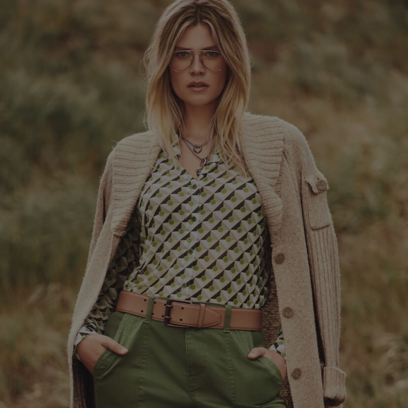 Model in background wearing Steady Cardigan in Wheat, Mosaic Mesh Top in Tile Print, Compass Pant in Army Green, and Jaguar Necklace in Gold. 
