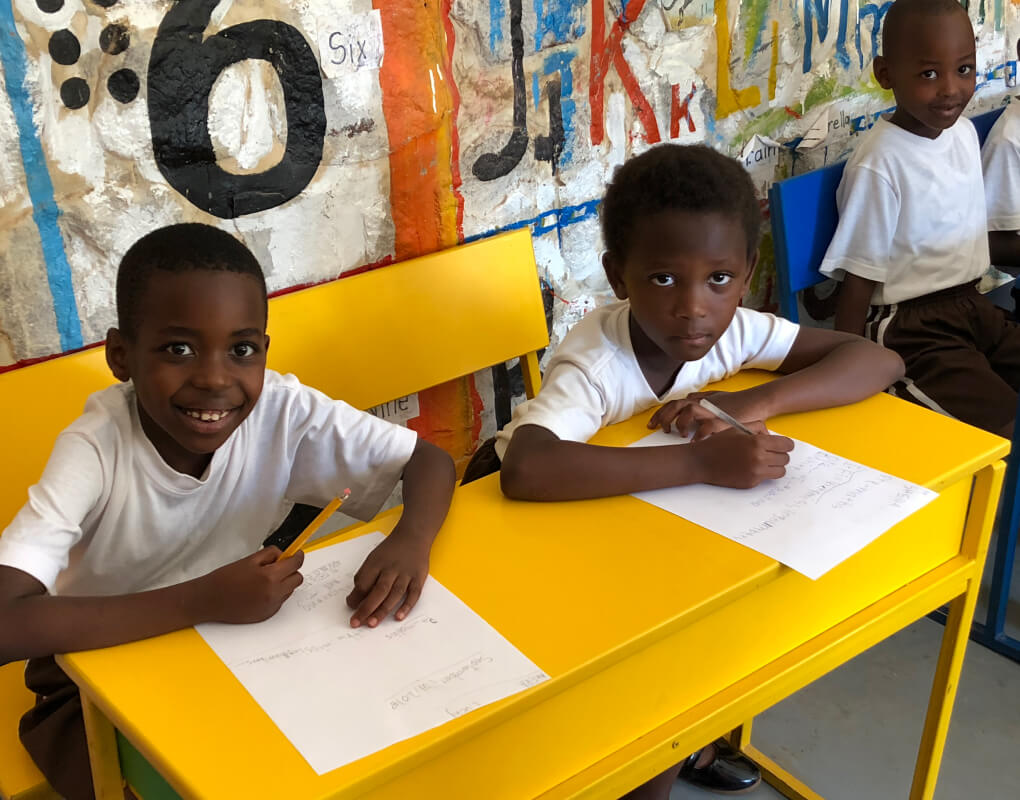 Two students sitting at desks smiling at the camera.