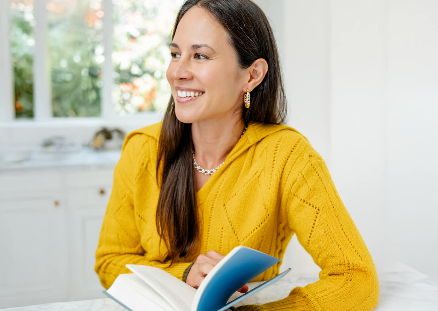 Woman in a yellow sweater with a book