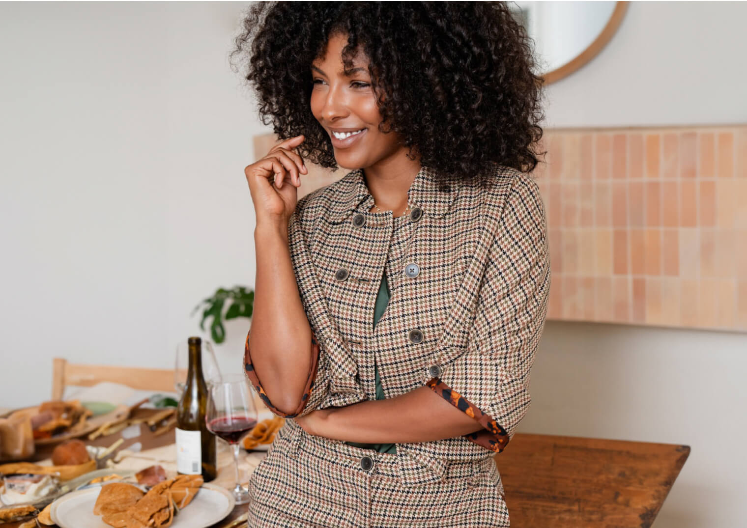 Woman leaning on a table of hor d'oeuvres and wine.