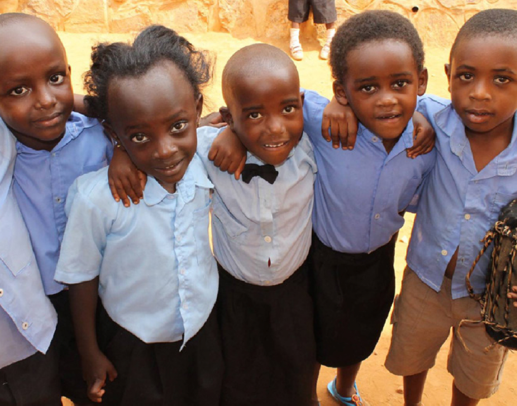 5 school children embracing each other and looking at the camera.